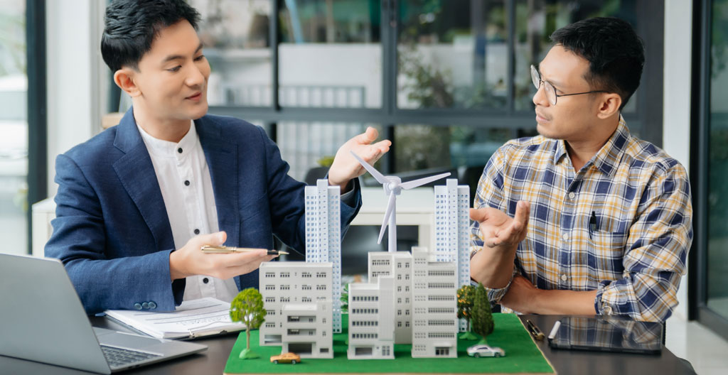 Mains tenant plusieurs devis papier avec des chiffres partiellement visibles, à côté d'une calculatrice et d'un stylo sur un bureau